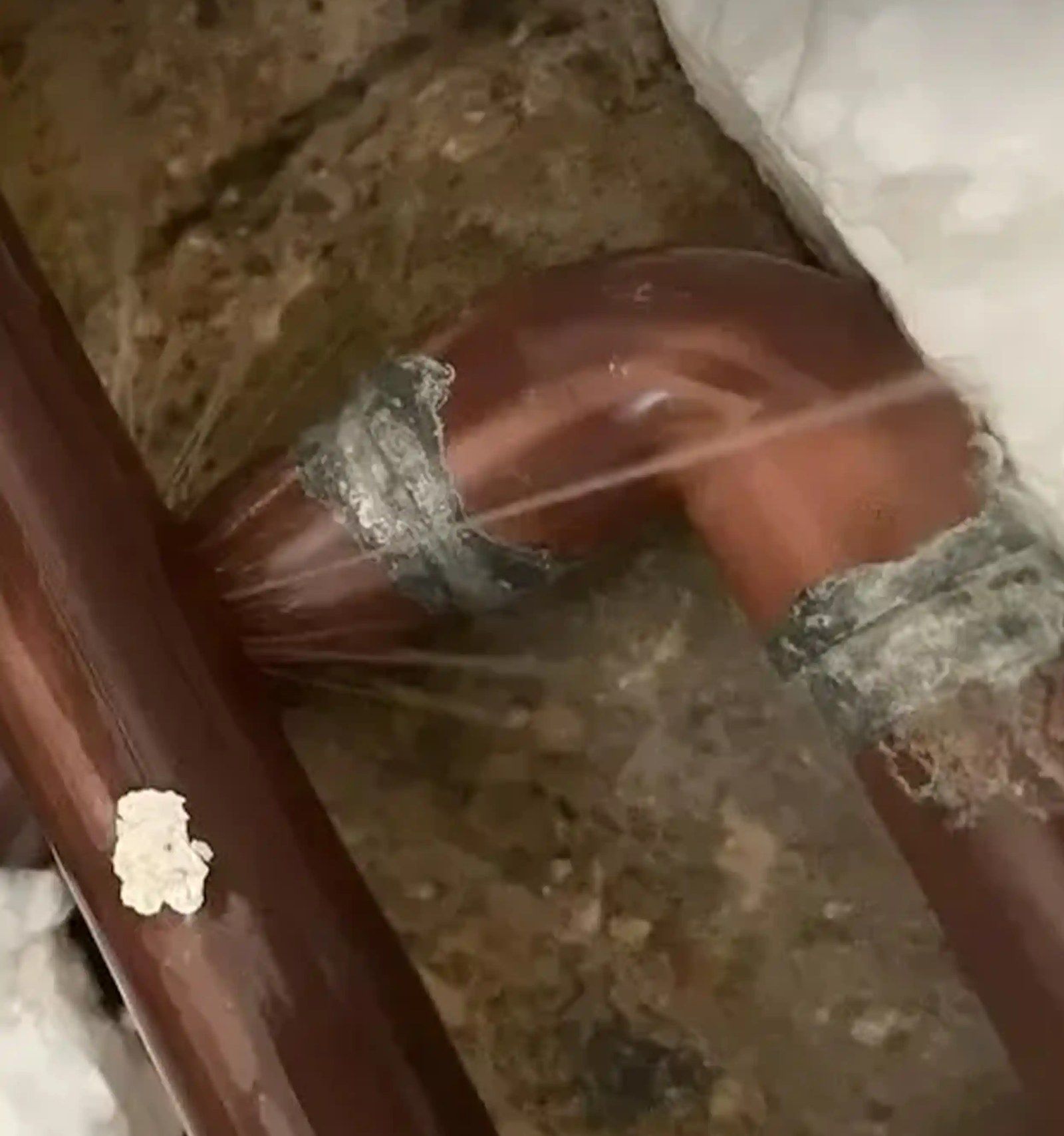 Water spraying from a joint on a copper pipe in an opened-up floor void